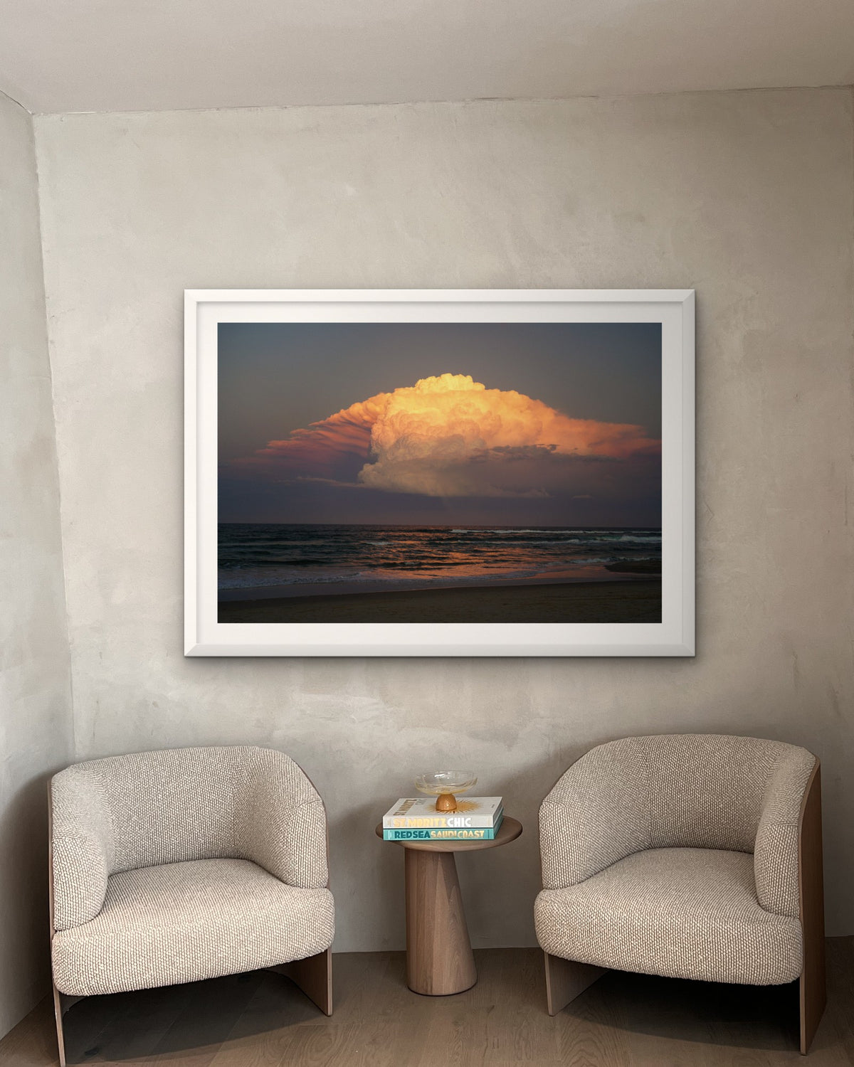 Where Skies Turn Gold landscape fine art print in a white frame centred above two armchairs and a small side table