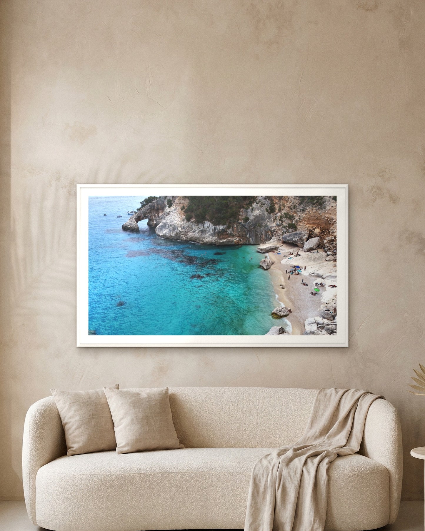 
                  
                    Arch and Deep Blue, Sardinia, framed with a 5 cm white border above a cream boucle sofa on a textured plaster wall
                  
                