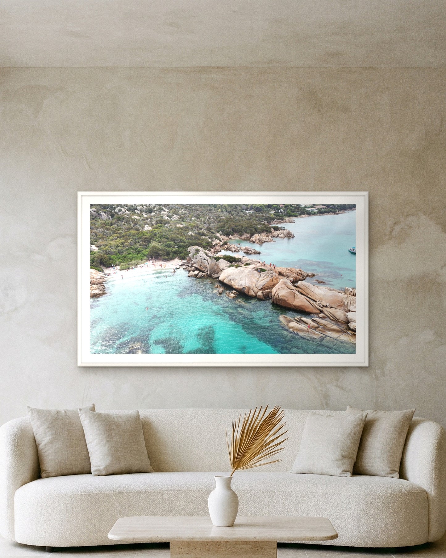 
                  
                    Granite Headland, Sardinia, framed with a 5 cm white border above a cream boucle sofa on a textured plaster wall
                  
                