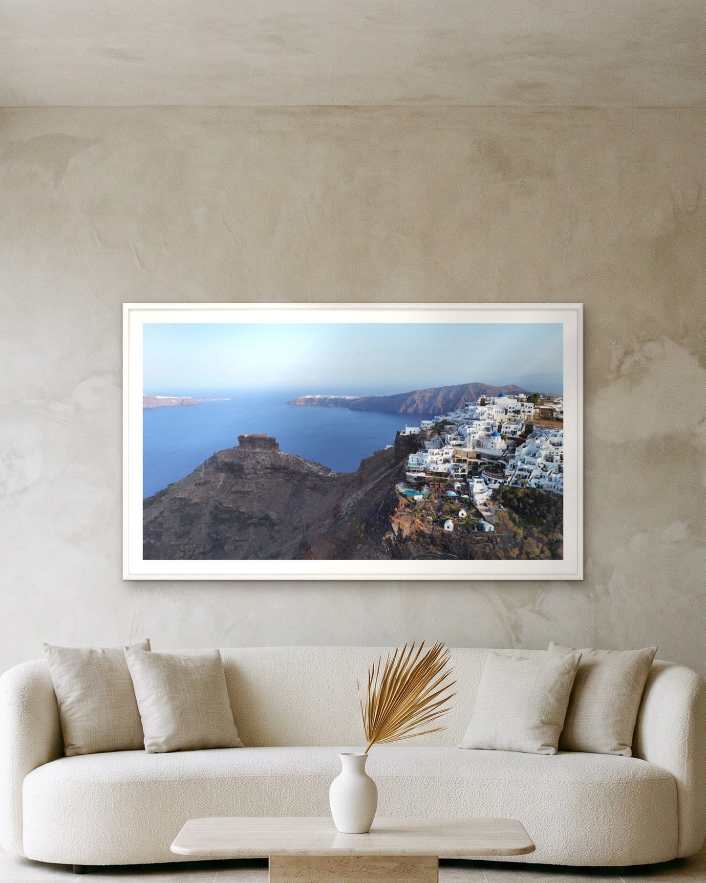 
                  
                    Skaros and Imerovigli, Santorini, framed with a 5 cm white border above a cream boucle sofa on a textured plaster wall
                  
                