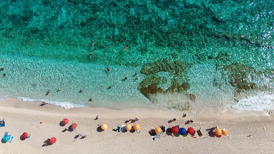 Colourful umbrellas on a white sand beach in Sardinia, from above