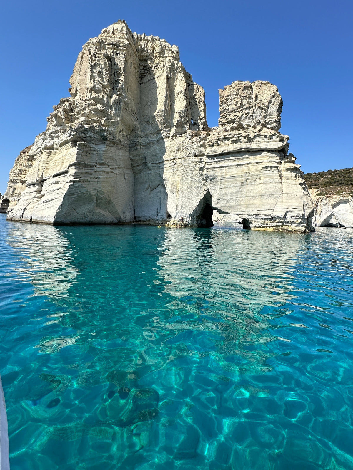 White cliffs rising from turquoise water in Milos